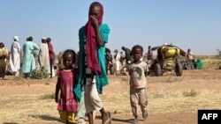 Разселена суданска жена с деца върви в лагер близо до Тавила, Северен Дарфур, на 11 февруари 2025 г., по време на войната между армията и паравоенните сили.