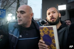 Andrew Tate (djathas) mban një Kuran teksa shoqërohet nga policia rumune, 26 janar 2023.
