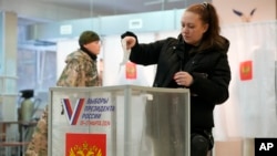 Një grua duke e hedhur votën në një qendër votimi në Shën Petersburg, Rusi, 15 mars 2024.