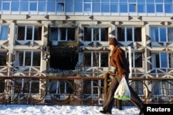 Женщина проходит мимо здания частной больницы, пострадавшего от ударов российских беспилотников. Киев, 5 января 2026 года