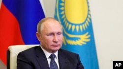 Президент России Владимир Путин на фоне флагов России и Казахстана подключается по видеосвязи к заседанию форума межрегионального сотрудничества 