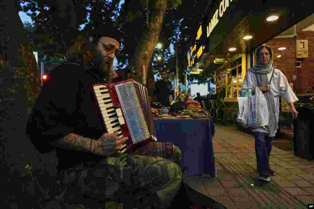 A street musician plays music on a sidewalk in northern Tehran.