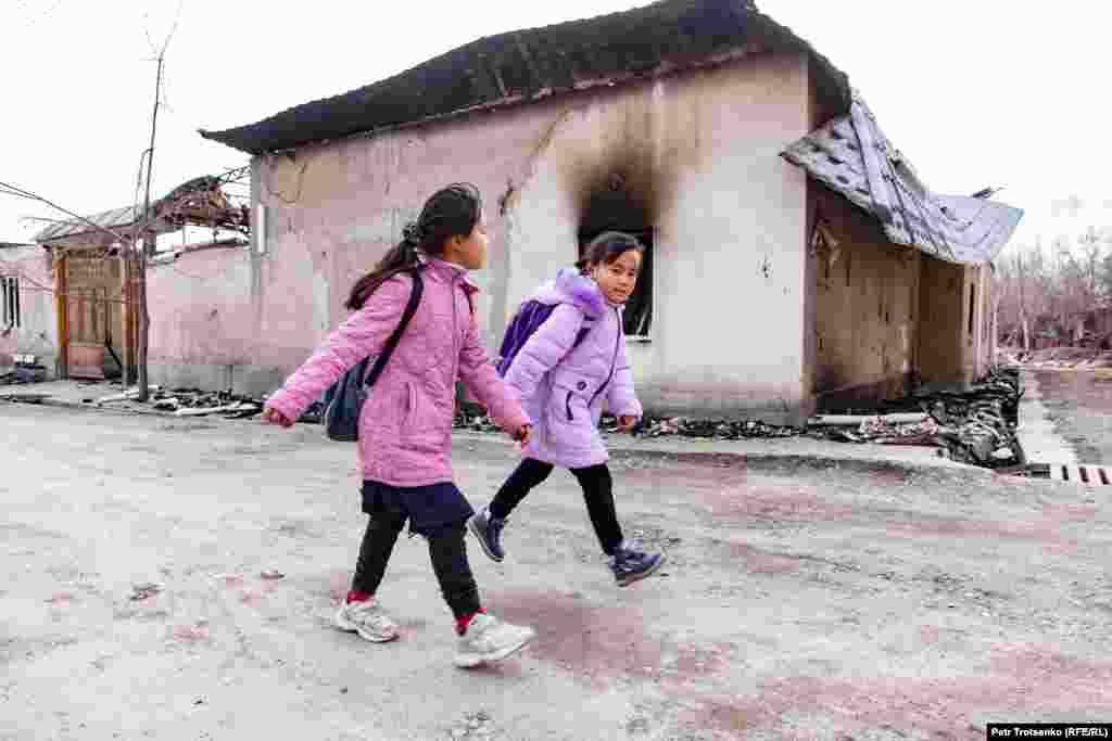 Dy nxënëse kalojnë pranë një shtëpie të djegur në Masanchi, në rajonin Zhambyl në Kazakistan më 26 shkurt, 2020, pasi më herët gjatë shkurtit shpërtheu një dhunë që u mori jetën disa personave. (REL). Autoritetet kazake nisën pothuajse 90 hetime, për të hetuar përplasjet etnike në rajonin Zhambyl, ku më 7 dhe 8 shkurt u vranë 11 persona. Më herët ata thanë se dhuna ndodhi ndërmjet qytetarëve lokalë kazakë nga minoriteti etnik Dugan &ndash; një grup myslimanësh me origjinë nga Kina. Dhuna vdekjeprurëse u shpërnda në fshatrat Sortobe, Masanchi, Auqatty dhe Bulan-Batyr.