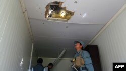 An Afghan policeman looks at a hole in the roof caused by a Taliban rocket following an attack in Ghazni Province on May 12.