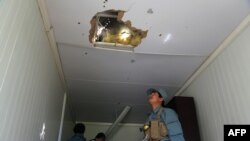 An Afghan policeman looks at a hole in the roof caused by a Taliban rocket following an attack in Ghazni Province on May 12.