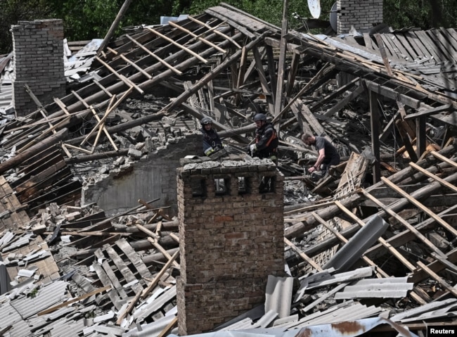 Punonjës ukrainas të shpëtimit duke punuar në vendin e një ndërtese banimi të goditur nga një sulm me dron rus në Zaporizhia më 30 maj.