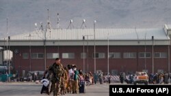 Një pjesëtar i Forcave Ajrore të SHBA-së udhëzon të evakuuarit për të hipur në një aeroplan të Forcave Ajrore të SHBA-së në Aeroportin Ndërkombëtar Hamid Karzai në Kabul, 24 gusht 2021. 