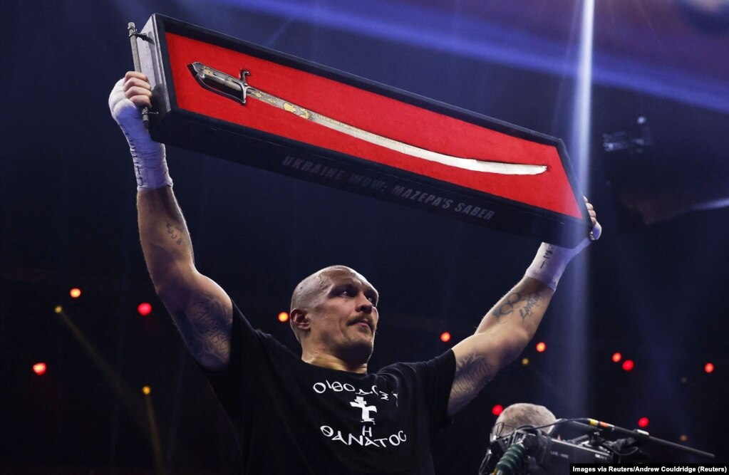 Олександр Усик з шаблею Мазепи святкує завоювання титулу чемпіона світу у надважкій вазі. Саудівська Аравія, 22 грудня 2024 року