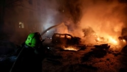 Пожарникар гаси огън в горящи автомобили близо до жилищна сграда, ударена от руски дрон в Харков, Украйна, 19 ноември 2025 г. 