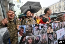 Parade attendees carry a banner bearing photographs of fallen soldiers in Kyiv on June 16.