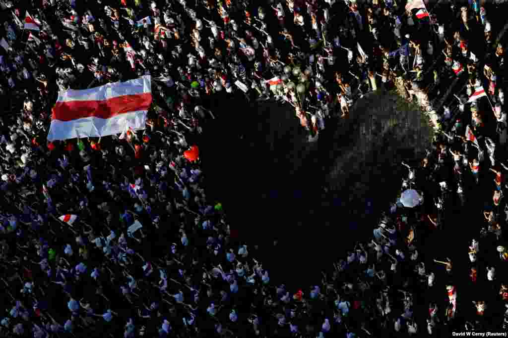 A large historical white-red-white flag of Belarus is pictured next to demonstrators forming a heart during a protest against the results of the Belarusian presidential election in Prague on August 16. (Reuters/David W. Cerny)