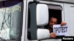 Vozač šlepera sa transparentnom na kojem piše "Protest" na graničnom prelazu Đevđelija u Severnoj Makedoniji, 26. januar 2026.