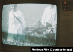 Captură de ecran cu imagini din 1992 din filmul „Noi suntem acasă”, produs de Moldova-Film, în care apar medicul Mihail Pîsla (stânga) și un coleg de-al său ducând pe targă un cadavru carbonizat.