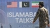 A Pakistani Ranger walks past a billboard for the US-Iran peace talks in Islamabad on April 12.