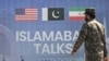 یک سرباز پاکستانی  در حال عبور از کنار بیلبوردی مربوط به مذاکرات صلح امریکا و ایران در اسلام آباد