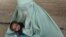 An Afghan refugee woman holds her baby at a United Nations repatriation center on the outskirts of Quetta, Pakistan.