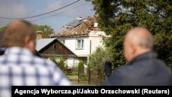 Banorët shikojnë shtëpinë e dëmtuar pasi një dron ose objekt i ngjashëm goditi ndërtesën banimi.