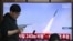 Një burrë kalon pranë një ekrani televiziv që tregon një transmetim lajmesh me pamje nga një testim rakektor të Koresë së Veriut, në një stacion treni në Seul, më 8 prill 2026.