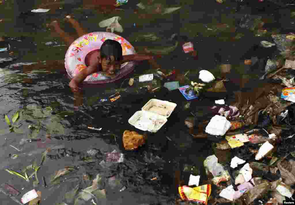 A child swims in the litter-strewn waters of Cilincing Beach in Jakarta, Indonesia.