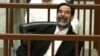 Saddam Hussein laughs while listening to testimony given by a defense witness (file photo)