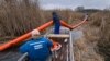 A vízügy szakemberei tisztítják a vizet a Szigetszentmiklós közelében található Ráckevei-Soroksári Duna-csatornába öntött olajtól 2020. december 14-én
