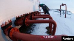 Un muncitor verificând valvele unei conducte de petrol a companiei Bashneft, pe un câmp petrolifer lângă Nikolo-Berezovka