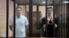 Maksim Znak (left) and Maryya Kalesnikava stand inside a defendants' cage as they attend a court hearing in Minsk on September 6.