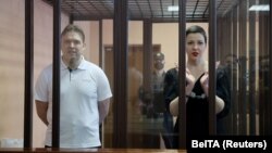 Maksim Znak (left) and Maryya Kalesnikava stand inside a defendants' cage as they attend a court hearing in Minsk on September 6.