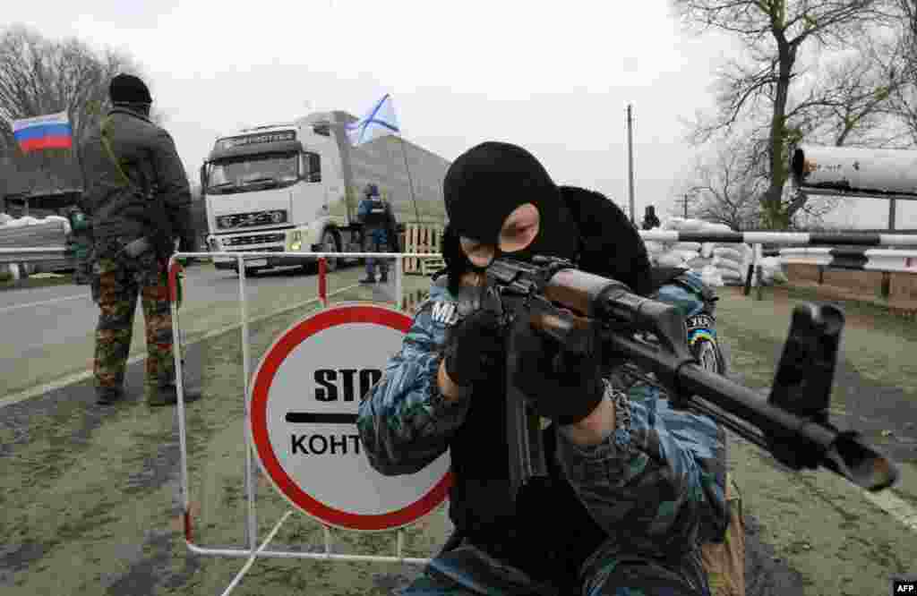 Qıtaiy Ukraina ve yarımada arasında blokpostlar qoyula. Kalaşnikov avtomatı ile silâlanğan &laquo;Berkut&raquo;nıñ sabıq hadimi Ermeni-Bazar şeeriniñ yanında. 2014 senesi fevral 28 künü