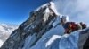 heavy traffic of mountain climbers lining up to stand at the summit of Mount Everest