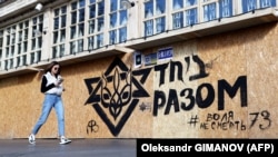 Жінка проходить повз графіті із зображенням герба України та зірки Давида з написом «Разом» на стіні в центрі Одеси, 12 жовтня 2023 року