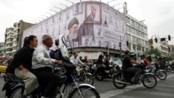 People ride motorcycles in Tehran on May 5 near a billboard featuring an image of the late Supreme Leader Ayatollah Ali Khamenei. 