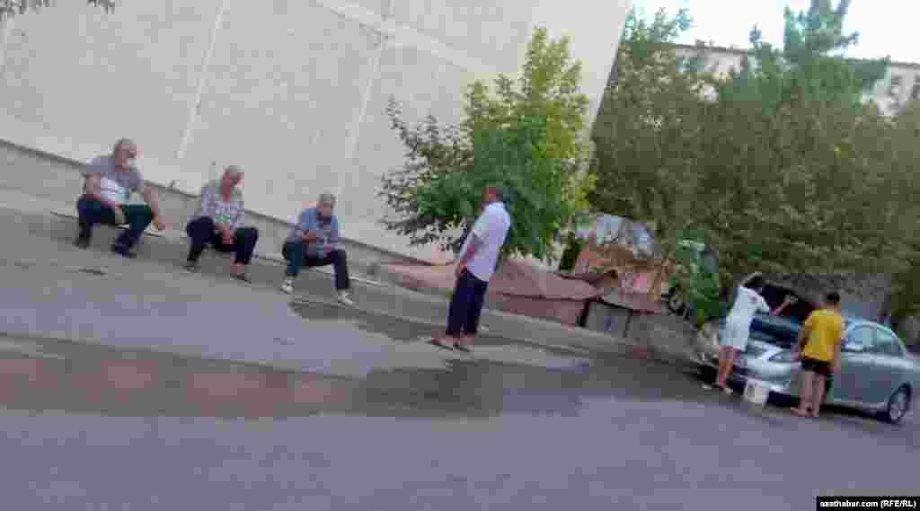 Köçede oturyp, özara söhbet edýän erkekler. Aşgabat, 2021.