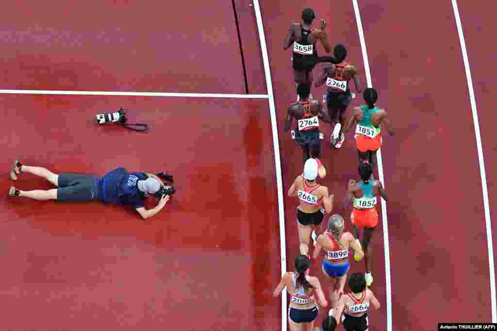 Фотограф намагається зазняти спортсменок, які змагаються на дистанції 5000 м, під час Олімпійських ігор у Токіо 2020, 30 липня 2021 року&nbsp;