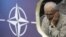 Beograd: Protestant protiv NATO-a iza postera sa znakom Alijanse, jun 2012.