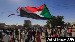 Demonstrant maše zastavom Sudana tokom demonstracija, Kartum, 25. novembar 2021.