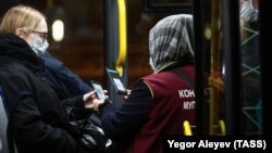 A bus conductor scans commuters' QR codes at a bus stop in Kazan, Russia.