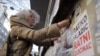 Aktivistkinja Aida Ćorović lijepi plakate na kojima piše Ratko Mladić ratni zločinac na protestu na Platou Milana Mladenovića u centru Beograda zbog murala koji slavi ovog osuđenog ratnog zločinca, 25. novembra 2021.