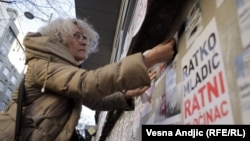 Aida Ćorović lepi plakate sa natpisom "Ratko Mladić ratni zločinac" na protestu u centru Beograda, novembar 2021. godine.