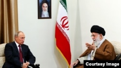 Ресей президенті Владимир Путин (сол жақта) 2017 жылы Иранға барған кезде аятолла Әли Хаменеимен кездескенде түсірілген фото. Жоғарыда қабырғада Ислам республикасының негізін қалап, 1989 жылы қайтыс болғанға дейін Иранды басқарған аятолла Рухолла Хомейнидің суреті ілініп тұр.