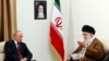Russian President Vladimir Putin meets Iranian Supreme Leader Ayatollah Ali Khamenei during a visit to Iran in 2017. A photo on the wall shows Khamenei's predecessor, Ayatollah Ruhollah Khomeini, who founded the Islamic republic and was supreme leader until his death in 1989.