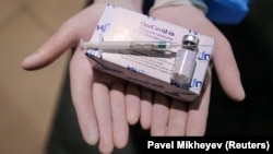 Медработник показывает шприц и коробку с флаконами с вакциной QazCovid-in против COVID-19 в пункте вакцинации, расположенном в торгово-развлекательном центре в Алматы. Казахстан, 27 апреля 2021 года.
