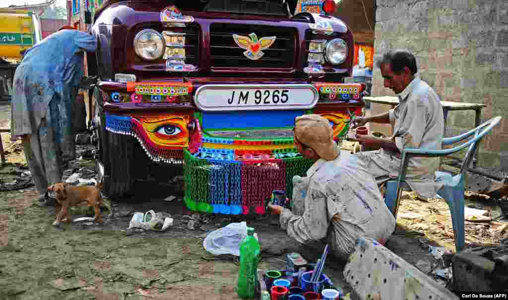 Master truck painter Hussain Noor (right) and other workers busy with a truck in Noor&#39;s workshop in Rawalpindi