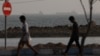 People walk at the beach, with vessels in the Strait of Hormuz visible near the beach of Bandar Abbas, Iran, August 26.