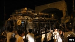 People gather near a bus that was set on fire by a mob in the southern Pakistani port city of Karachi on May 20.