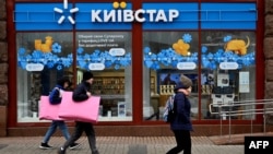 Ljudi prolaze pored prodavnice Kyivstar, najveće ukrajinske telekomunikacione kompanije, u Kijevu 12. decembra.