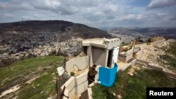 An Israeli soldier casts his ballot for the parliamentary elections behind a mobile voting booth at an army base on Mount Gerizim, near the West Bank City of Nablus, on March 17.