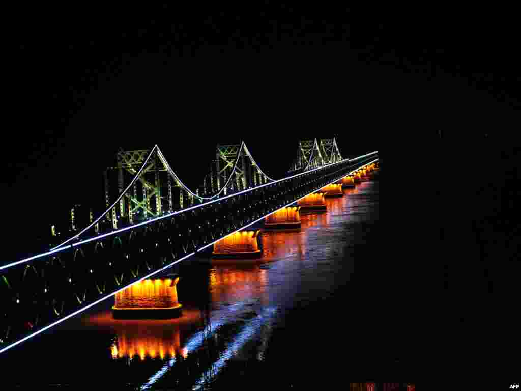 A bridge to nowhere in the middle of the Yalu River, which separates North Korea from China. The bridge, which was lit up from the Chinese side on November 24, only reaches half way across the river after it was bombed by the United States in 1950 during the Korean War. Photo by Frederic J. Brown for AFP 