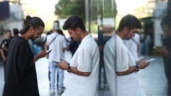 Iranian men check their phones in Tehran after a reported reopening of international internet access on May 27.