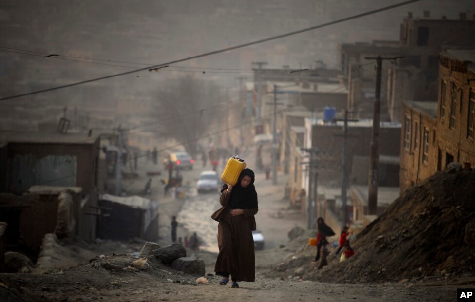 Një grua në Kabul duke e bartur ujin në një shishe plastike teksa kthehet në shtëpinë e saj.